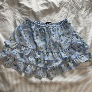 Blue floral ruffle mini skirt with elastic waistband and tie detail. Size: M